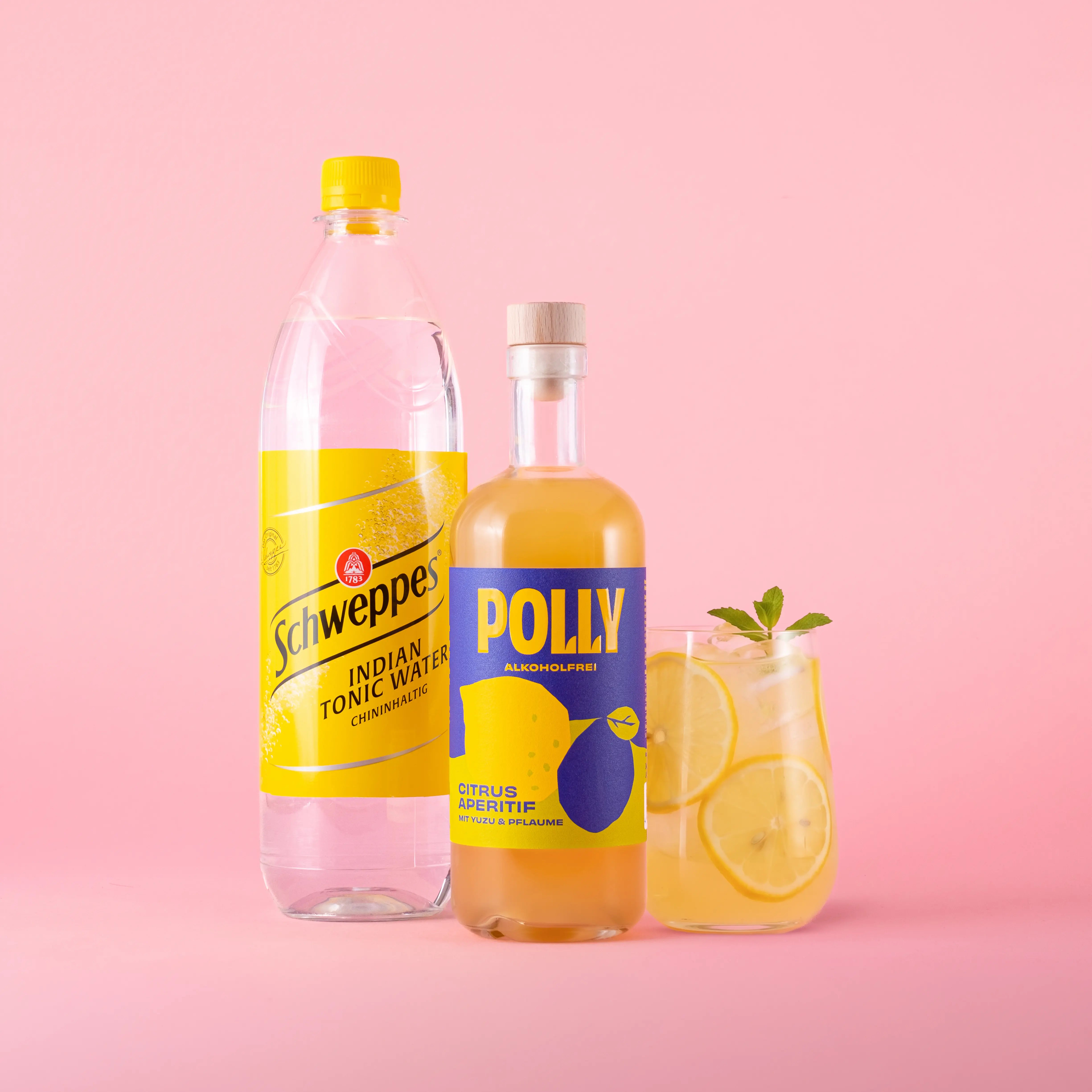 Starter Set für alkoholfreien Citrus Tonic mit einer Flasche POLLY Citrus Aperitif und einer Flasche Schweppes Indian Tonic Water sowie einem angerichteten Glas mit Citrus Tonic Drink