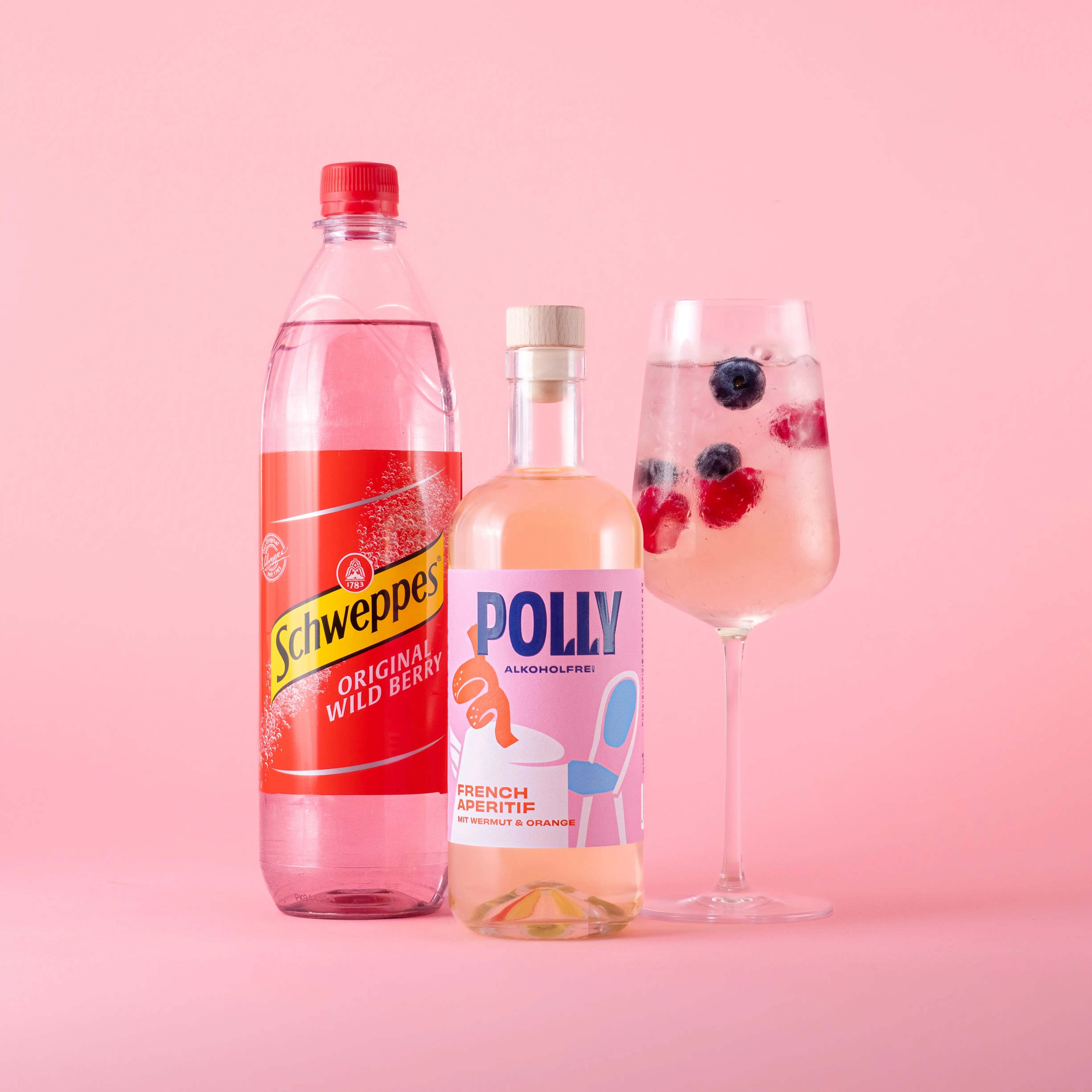 Starter Set für alkoholfreien Wildberry Spritz mit einer Flasche POLLY French Aperitif und einer Flasche Schweppes Original Wild Berry sowie einem angerichteten Glas mit Wildberry Spritz Drink